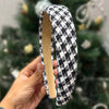 A black and white houndstooth hair band with a gold heart charm.