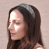 Woman wearing a patterned headband against a neutral background