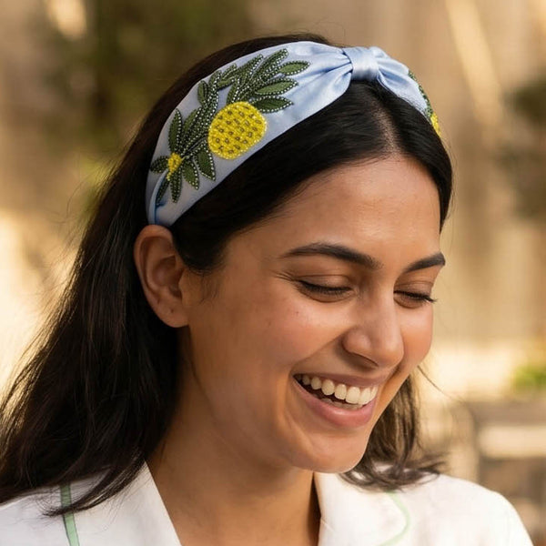 Bright lemon headband with intricate green embroidery on soft blue satin base