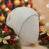 White knit beanie on a mannequin head with Christmas decorations and lights in the background