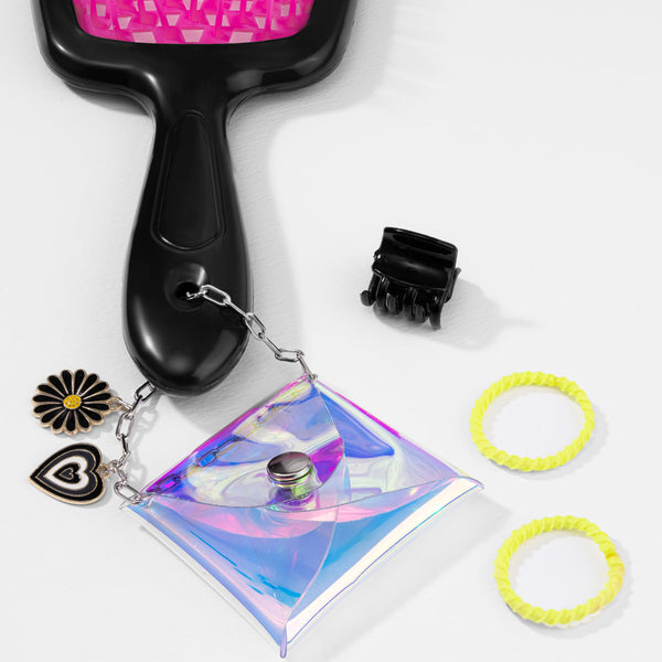 Black hairbrush, hair ties, and a small pouch with charms on a white background