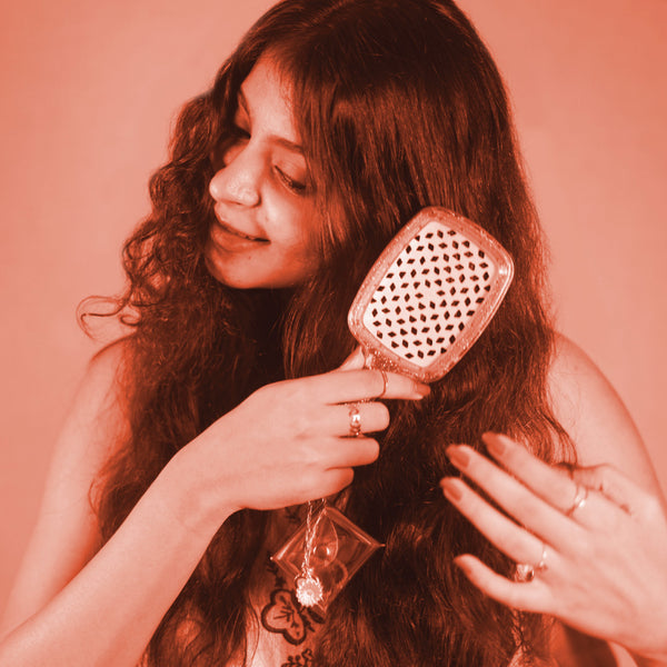 Woman holding a hairbrush against a pink background