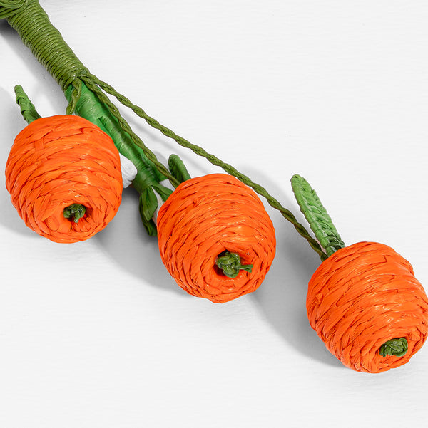 Three orange paper carrots with green stems on a white background