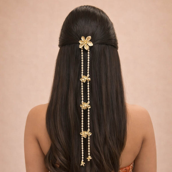 Woman with long dark hair wearing a decorative gold hairpiece against a beige background