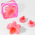 Set of pink flower-shaped hair accessories with a clear pink case on a white background