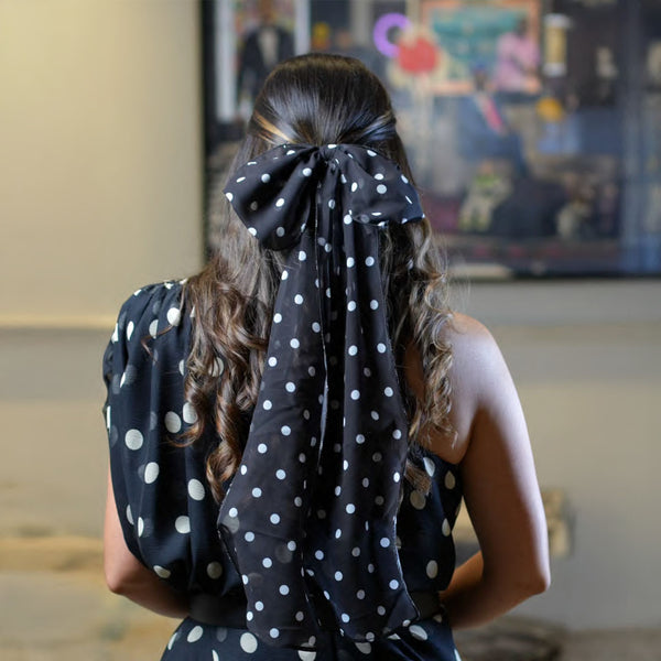 Person wearing a black polka dot headscarf with a blurred background