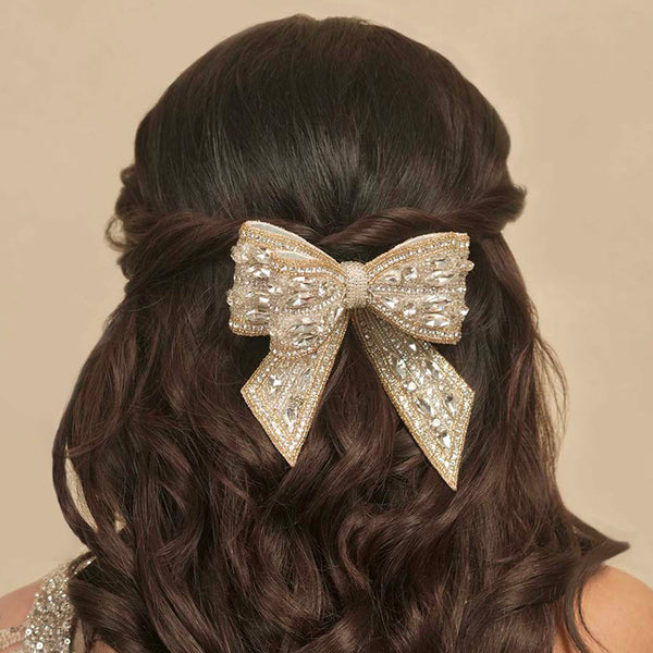 Hair bow with sequins on a person with wavy hair against a beige background
