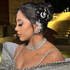 Woman in a silver embellished outfit with intricate hairpiece and jewelry.