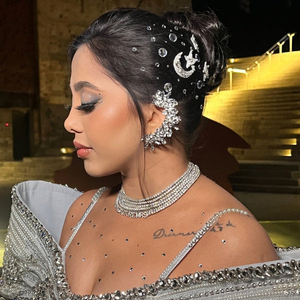 Woman in a silver embellished outfit with intricate hairpiece and jewelry.