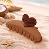 Brown hair clip with heart-shaped design on a sandy background