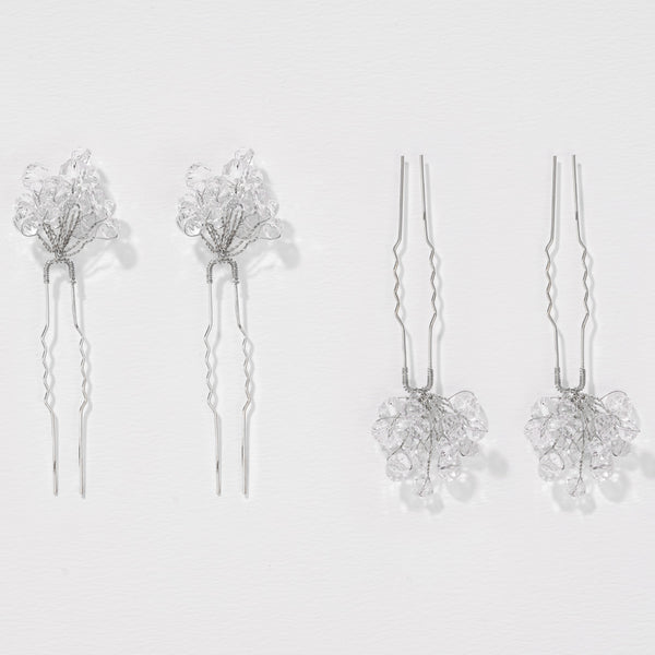 Set of four silver hairpins with floral designs on a light gray background