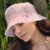 Woman wearing a pink bucket hat with decorative elements outdoors
