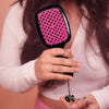 Person holding a hairbrush with pink bristle head and black handle