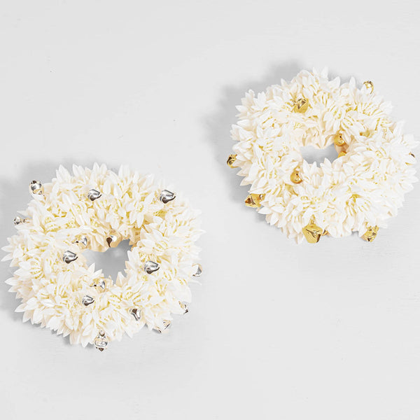 Pair of white floral earrings with gold and silver accents on a light gray background