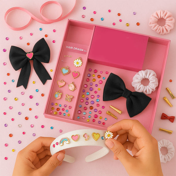 A selection of hair accessories including charms, crystals, and pom poms arranged neatly in a pink box, with a person holding a hair band decorated with charms.
