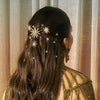 Woman with intricate hair styling and decorative hairpins against a neutral curtain background