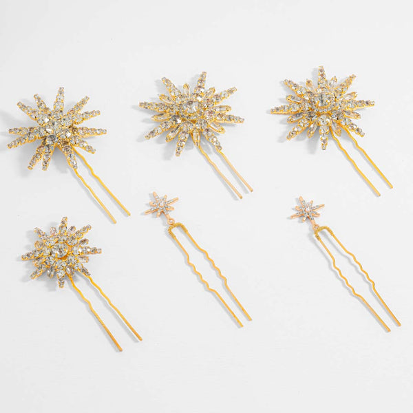 Set of six gold hairpins with star-shaped decorative ends on a light gray background