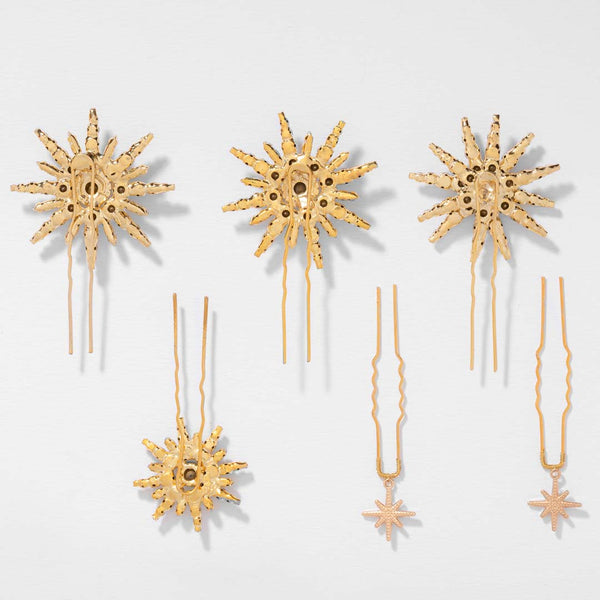 Set of gold star-shaped hairpins on a light gray background