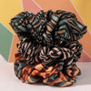Three patterned scrunchies on a colorful geometric background
