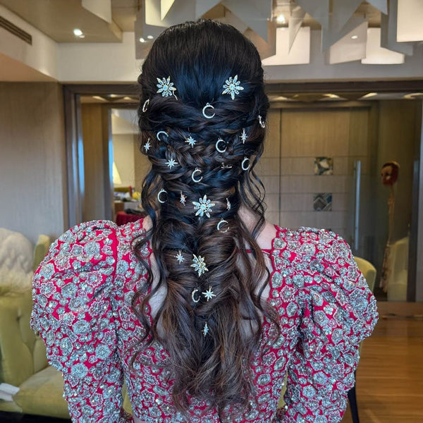 Person with intricately styled hair adorned with decorative hairpins in a room setting.