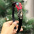HAIRBAND EMBELLISHED WITH BROACH AND RED & BLACK FEATHER