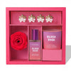 Pink gift set with 'Blush Rush' perfume and hair product, red roses, and decorative earrings.