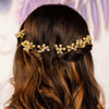 A woman's hair styled with four gold embellished pearl hair pins.