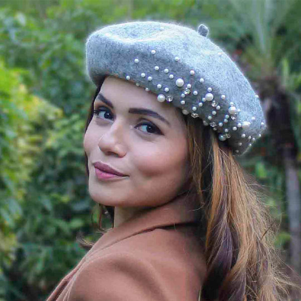 Woman wearing a gray beret with pearl embellishments outdoors