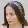 Woman wearing a zebra print headband against a neutral background