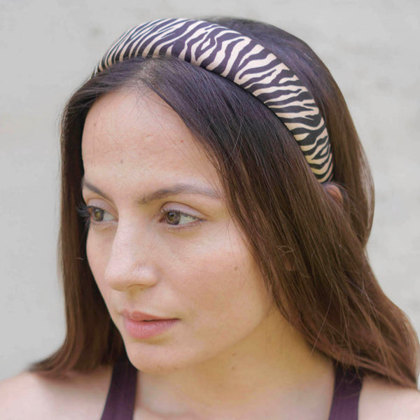 Woman wearing a zebra print headband against a neutral background