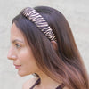 Woman wearing a zebra-striped headband against a neutral background
