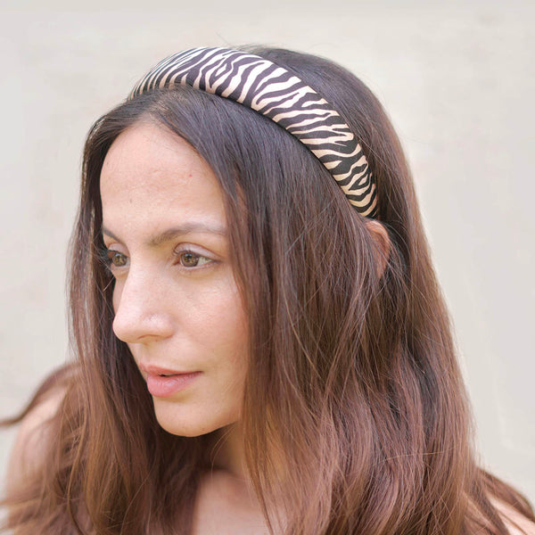 Woman wearing a zebra-striped headband against a neutral background