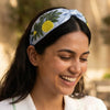 Bright lemon headband with intricate green embroidery on soft blue satin base
