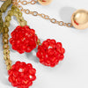 Close-up of red floral earrings with gold chain on a light background