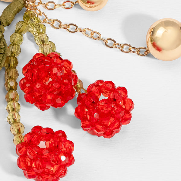 Close-up of red floral earrings with gold chain on a light background