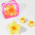 Yellow flower-shaped hair accessories with a pink 'Hair Drama Co.' pouch on a white background