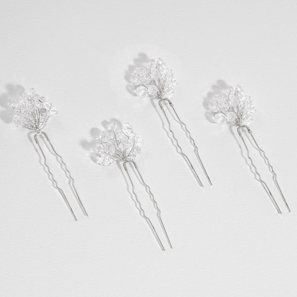 Set of five silver hairpins with floral designs on a light gray background