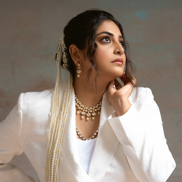 Woman wearing traditional jewelry and a white outfit against a neutral background