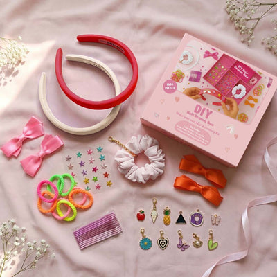 Hair accessories and DIY kit on a pink surface with flowers.