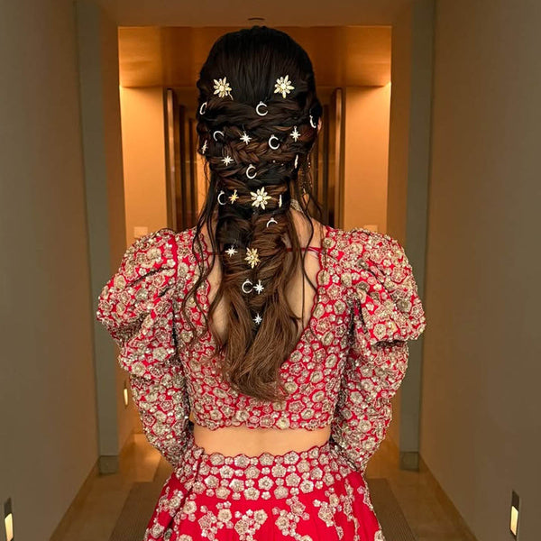 Person wearing a red floral outfit with decorative hair accessories in a hallway.