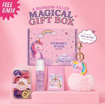 A pink unicorn-themed gift box set displayed on a pink background. The set includes a large box labeled 'Unicorn Magic Gift Box,' a pink fluffy unicorn keychain, a small pink bottle labeled 'Sparkle,' a clear container of colorful hair ties, and a cloud-shaped tag that reads 'For Girls Who Sparkle Extra Bright.